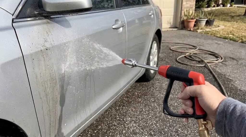 Pocket Hose spray wand being used to rinse dirt from the side of a vehicle